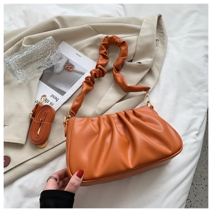 Close-up of orange pleated cloud bag texture with detachable shoulder strap and leather detail