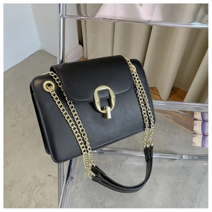 Close-up of black crossbody chain bag featuring golden D-shaped buckle and textured leather