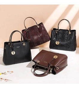 Detail of elegant handbags in smooth and snakeskin textures with gold pendants