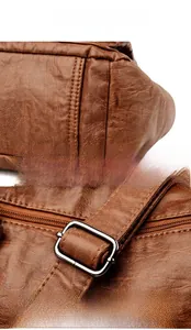 Detail view of smooth brown leather corners and metal adjustment buckle for handbag