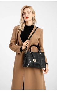 Detail of black snake-embossed leather handbag featuring a gold letter F pendant