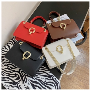 Close-up of four-color chain shoulder bags with polished gold buckles on a stylish desk