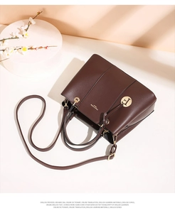 Close-up of dark brown leather handbag with gold metal logo and fine stitching details