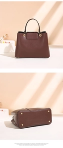 Detail view of brown leather handbag featuring golden bottom studs and hardware accents