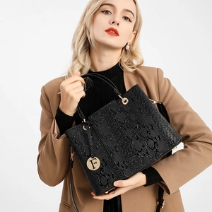 Detail of black faux leather handbag with crocodile pattern and golden F pendant