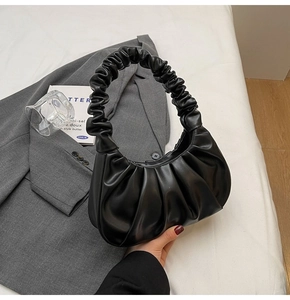 Detail of ruched black croissant shoulder bag on a minimalist fashion lifestyle setting