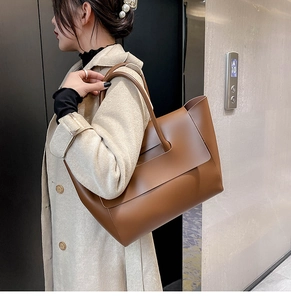 Detailed view of brown leather tote bag with unique hollow handle and flap closure design