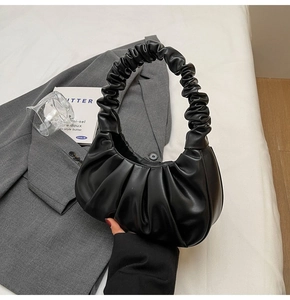 Detail of black pleated handle on hobo bag with cloud texture and premium leather finish
