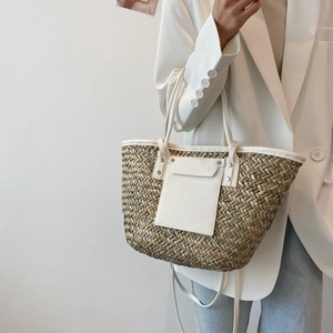 Woven straw tote bag with white leather trim styled on a model for a beach vacation look