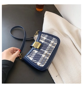 Detail of navy tweed crossbody bag featuring a golden square lock and woven texture