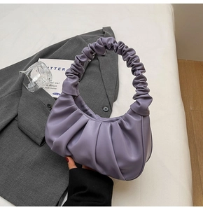 Detailed view of the lavender purple pleated cloud bag on a stylish grey blazer background