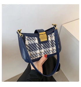 Close-up of navy leather and tweed shoulder bag with gold metal buckle detail