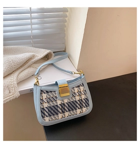 Detail of light blue tweed shoulder bag showing premium texture and golden buckle lock