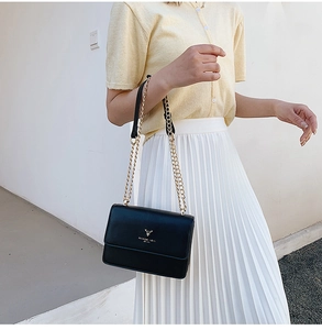 Detail of black PU leather bag featuring a gold deer logo and metallic chain strap