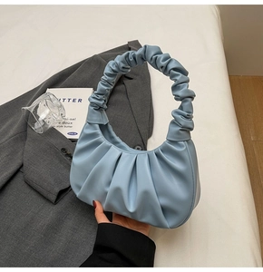 Close-up of light blue ruched cloud bag texture on gray blazer for lifestyle display