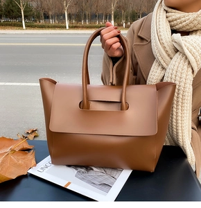 Brown matte leather tote bag detail with unique cut-out handle and stylish flap closure