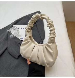 Detail of a creamy beige pleated hobo bag texture on a stylish blazer background