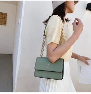 Detail of grey-green leather crossbody bag featuring gold chain and deer head logo