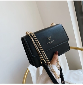 Detail of black leather square bag with gold deer logo and metallic chain strap