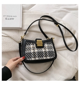 Detailed view of black and white tweed crossbody bag with golden buckle and leather strap