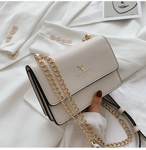 Detail view of cream flap bag featuring a golden deer logo and multi-layer gusset design