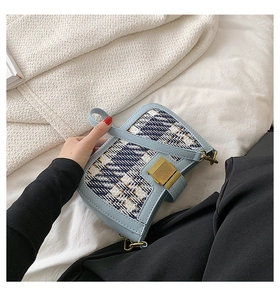 Close-up of light blue tweed crossbody bag with gold-tone hardware and rotating lock