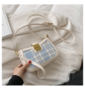 Detail of tweed flap on beige crossbody bag featuring a golden square metal lock buckle