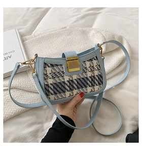 Detail of tweed texture and golden metal lock on light blue faux leather shoulder bag