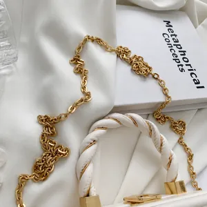 Detalle de bolso blanco con correa de cadena dorada y asa superior trenzada
