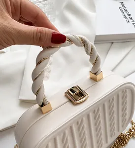 Detalle de cerca del bolso blanco crema con asa de cuerda trenzada y herrajes dorados