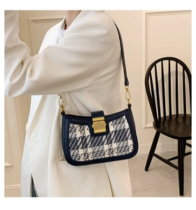Detail of tweed crossbody bag with gold lock worn by a model in a white blazer