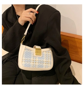 Detail of light blue and white tweed shoulder bag with golden metal buckle on model