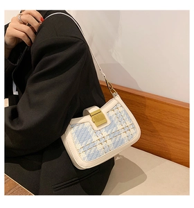Close-up of small crossbody bag featuring white leather and blue tweed with gold clasp