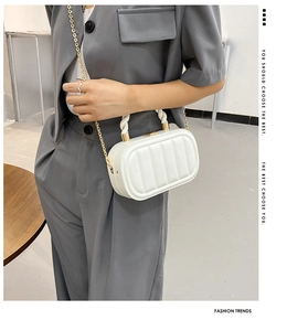Close-up of a white padded square handbag with golden chain strap and twisted top handle