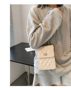 Detail view of quilted cream PU leather phone bag with gold chain and twist lock