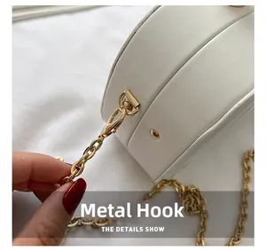 Detailed close-up of premium golden hardware hook and chain on white leather handbag