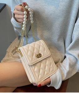 Detail of beige quilted mini bag with gold twist lock and elegant white pearl strap handle