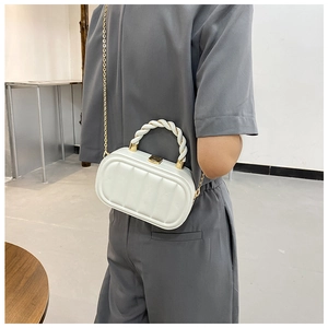 White quilted cross-body bag with golden chain and twisted handle worn by model