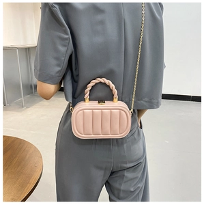 Detail of light pink oval quilted chain bag with spiral top handle and gold hardware