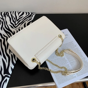White minimalist chain flap bag with golden metallic shoulder strap and sleek design