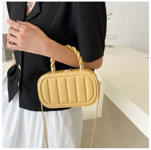Detail of light yellow pleated handbag with braided handle and gold metal chain strap