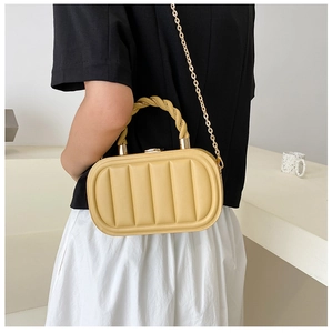 Detail of yellow candy-colored handbag with pleated texture and gold chain strap