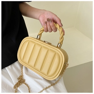 Detail of yellow quilted leather handbag with twisted handle and gold chain strap