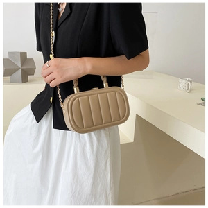 Detail of khaki quilted handbag with vertical stitching and gold chain strap in minimalist setting