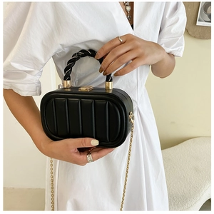 Detail of black pleated mini bag featuring a gold clasp and woven handle texture