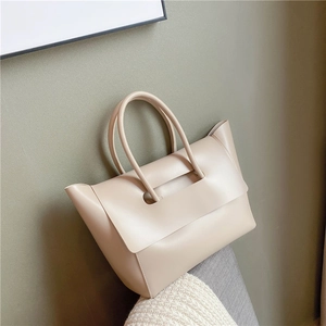 Elegant beige leather handbag in minimalist style with unique handle flap design