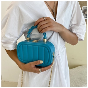 Detail of sky blue handbag with vertical textures and gold chain strap close-up