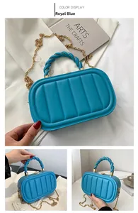 Close-up of royal blue quilted handbag with braided handle and gold chain strap