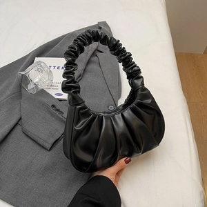 Minimalist black pleated cloud bag in premium PU leather on grey suit background