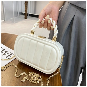 Close-up of white textured handbag with gold hardware and stylish twisted handle details